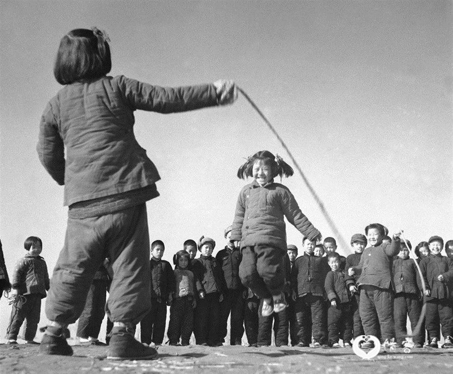1956年12月，河北省高阳县邢果庄村的小学生们在空地上跳绳。