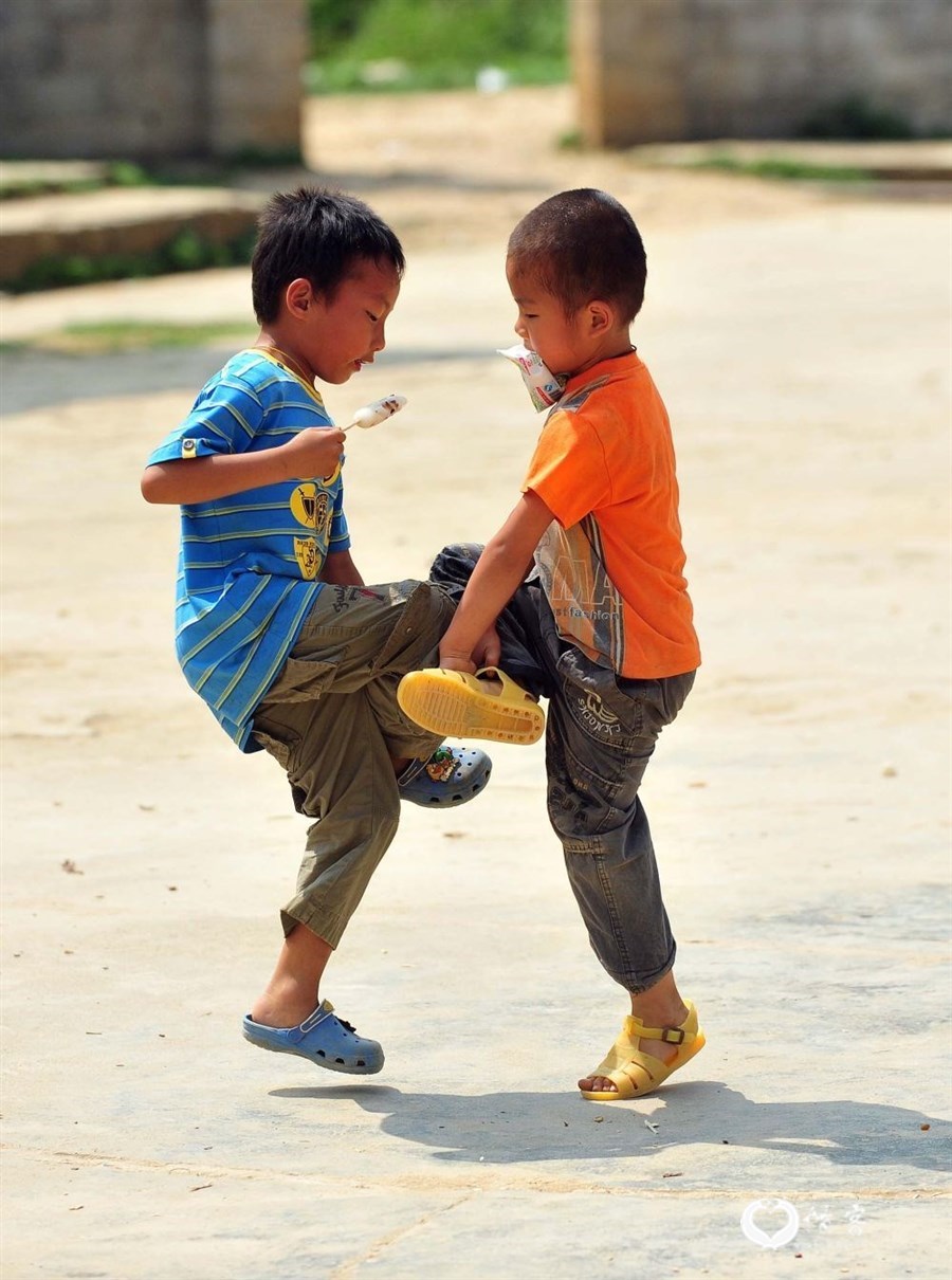 2012年5月3日，在广西大化瑶族自治县大化镇仁良村弄良小学，两名小学生一边吃零食，一边玩“斗驹”。